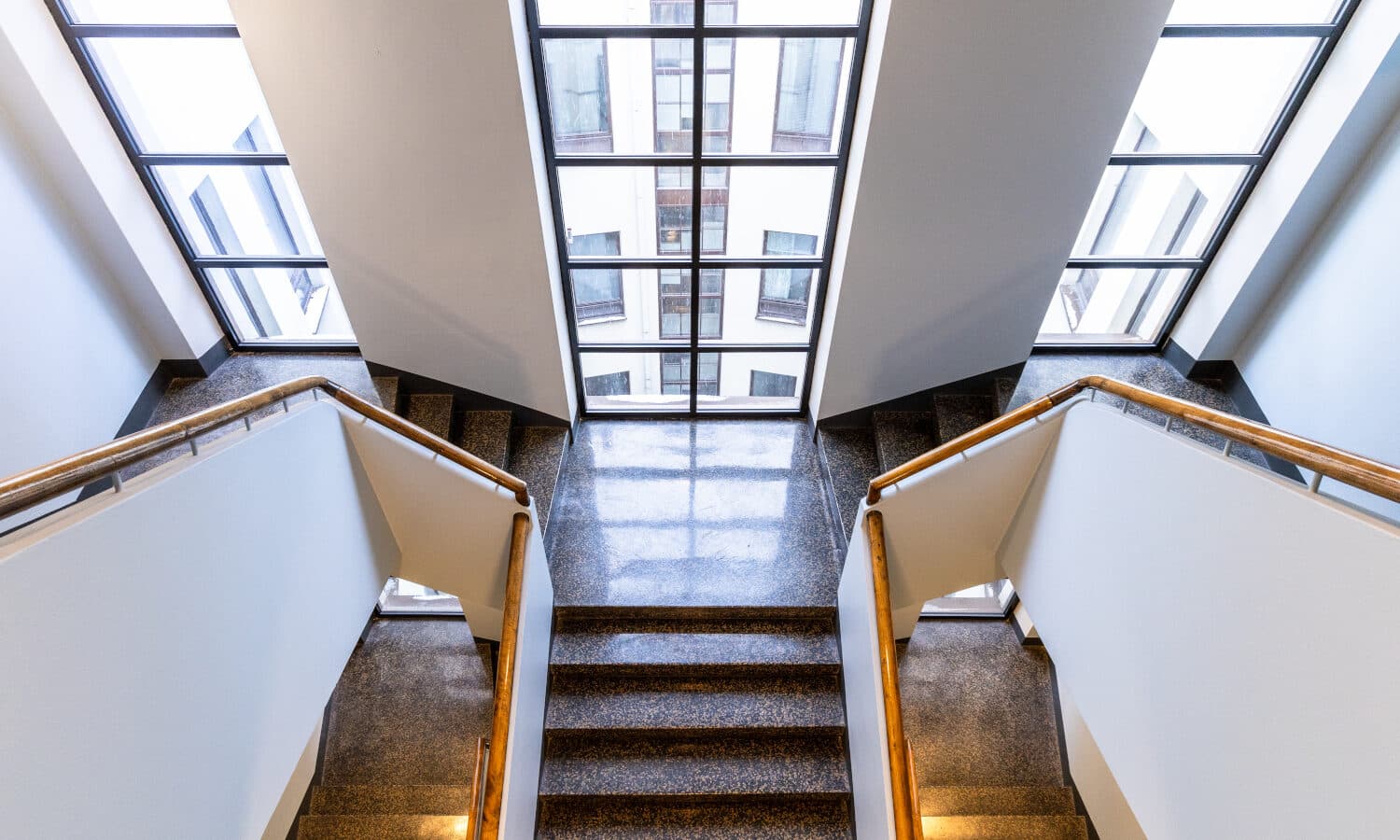 Vanhaa arvokkuutta henkivän rakennuksen rappukäytävä. Ikkunat ovat korkeat ruudulliset.